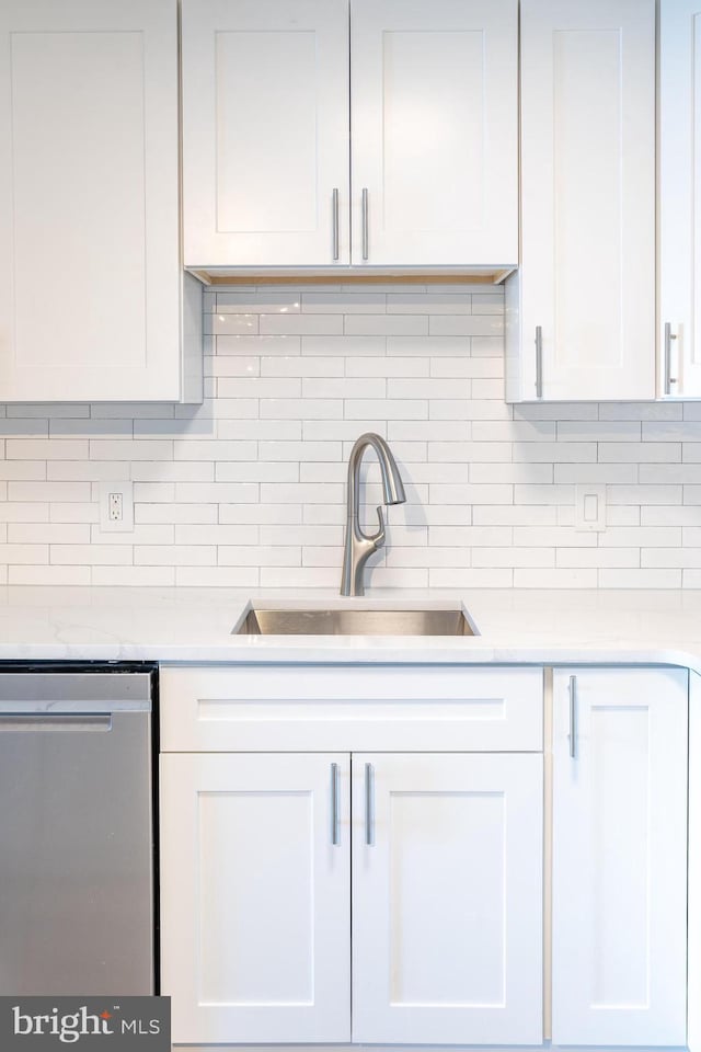 kitchen featuring a sink, white cabinetry, light countertops, and stainless steel dishwasher