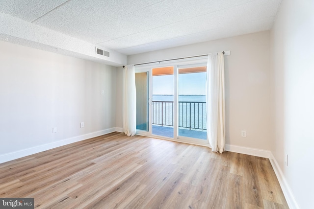 unfurnished room featuring light hardwood / wood-style flooring and a textured ceiling