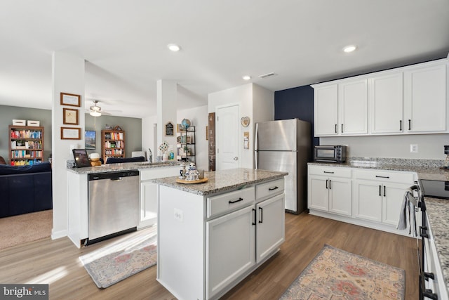 kitchen featuring white cabinets, a center island, light wood-type flooring, and stainless steel appliances