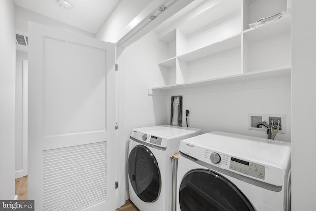 laundry room with light wood-type flooring and washing machine and clothes dryer