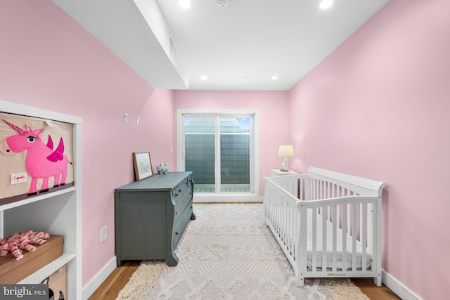 bedroom featuring light hardwood / wood-style flooring and a crib