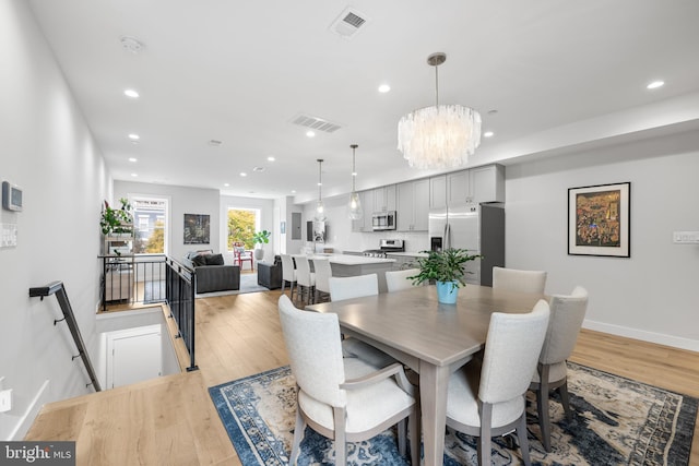 dining area featuring light wood-type flooring and an inviting chandelier