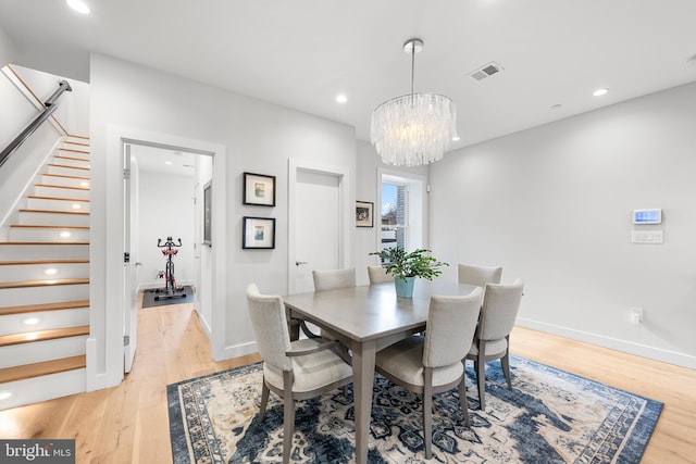 dining space with light wood-type flooring and an inviting chandelier