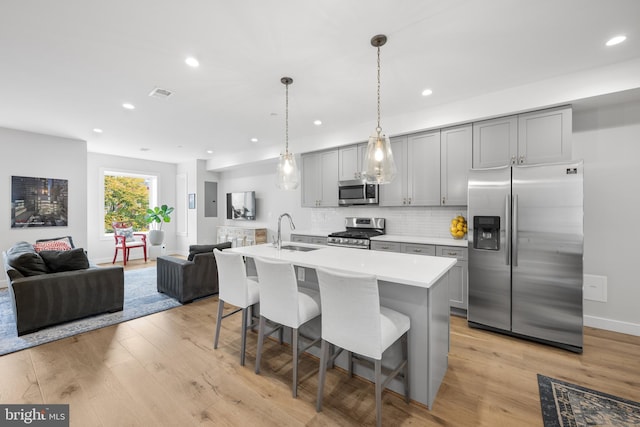 kitchen featuring gray cabinetry, sink, an island with sink, and appliances with stainless steel finishes