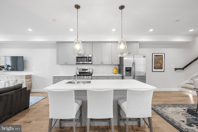 kitchen with gray cabinetry, sink, stainless steel appliances, and light wood-type flooring