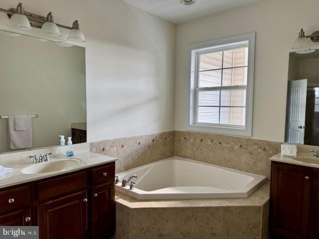 bathroom featuring vanity and a relaxing tiled tub