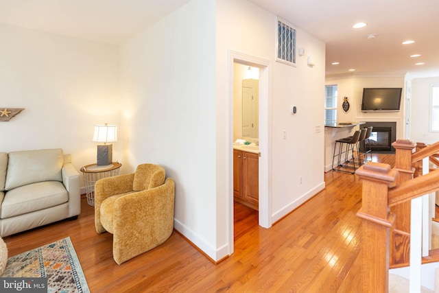 living area featuring light hardwood / wood-style floors, ornamental molding, and sink