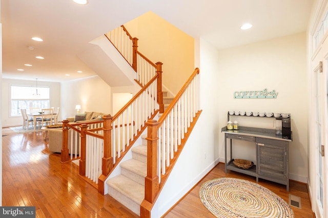 staircase with hardwood / wood-style floors and ornamental molding