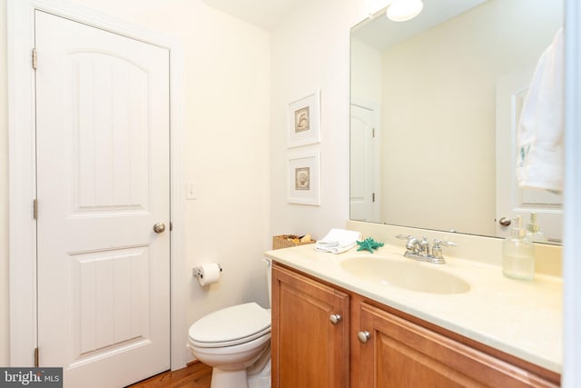 bathroom featuring wood-type flooring, vanity, and toilet