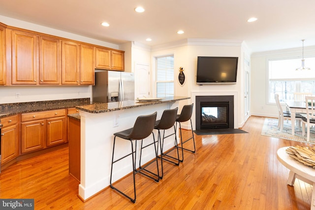 kitchen with stainless steel refrigerator with ice dispenser, light hardwood / wood-style floors, a kitchen island, and pendant lighting