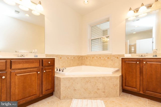 bathroom with tile patterned flooring, vanity, and tiled tub