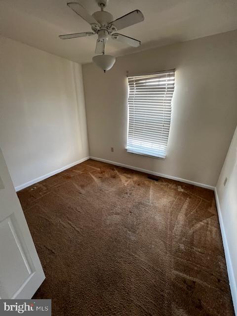 carpeted spare room featuring ceiling fan