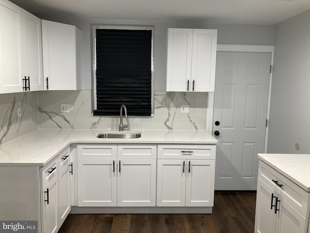 kitchen with dark hardwood / wood-style floors, white cabinetry, tasteful backsplash, and sink