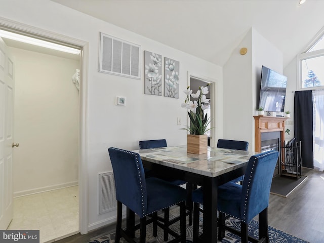 dining space with hardwood / wood-style floors and vaulted ceiling