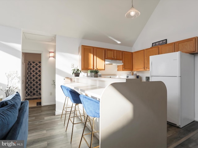 kitchen featuring kitchen peninsula, pendant lighting, high vaulted ceiling, white fridge, and dark hardwood / wood-style floors