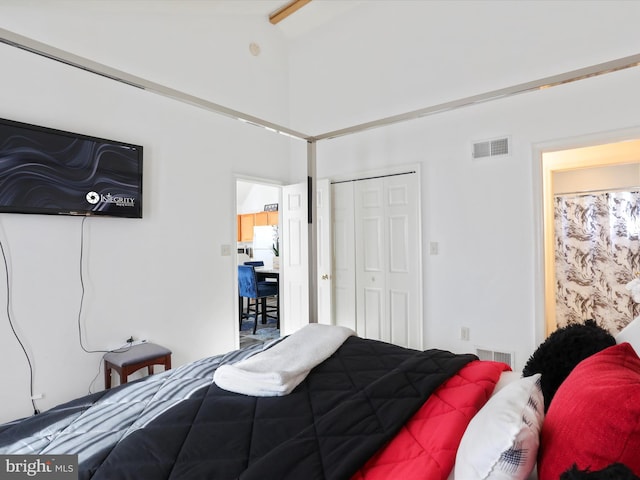 bedroom with lofted ceiling with beams, white fridge, and a closet