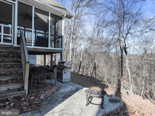 view of patio with ceiling fan, area for grilling, an outdoor fire pit, and a sunroom