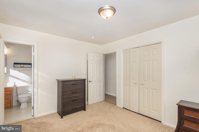 bedroom featuring ensuite bath, a closet, and light colored carpet