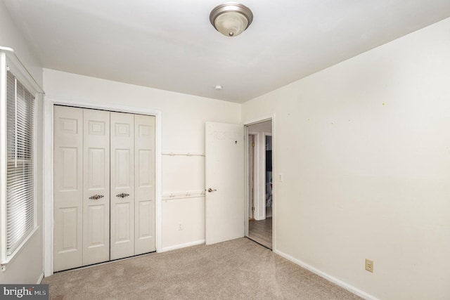 unfurnished bedroom with light carpet and a closet