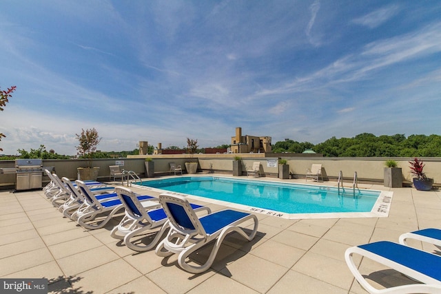 view of swimming pool featuring a grill and a patio