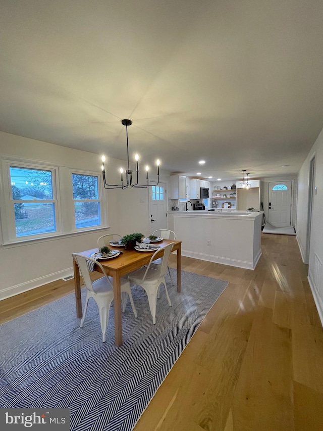 unfurnished dining area featuring light wood-type flooring and an inviting chandelier