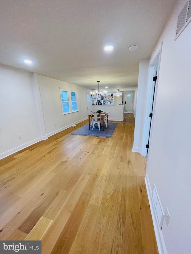 unfurnished dining area featuring light wood-type flooring and an inviting chandelier