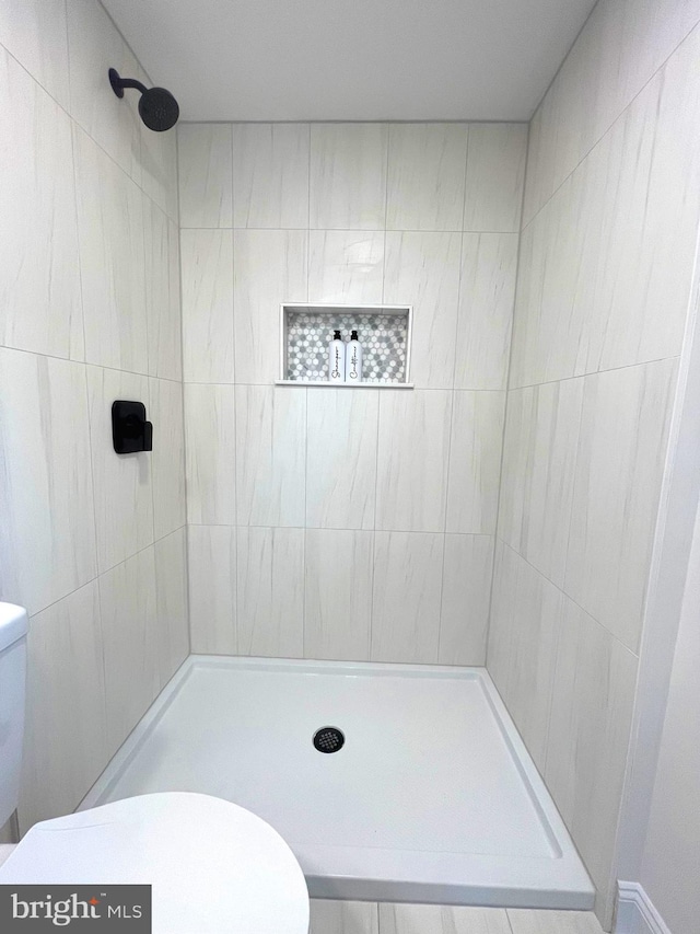 bathroom featuring a tile shower and toilet