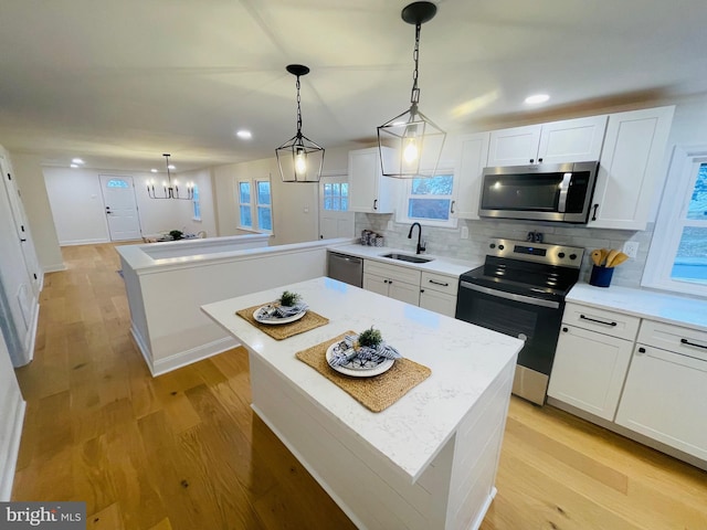 kitchen with a center island, backsplash, sink, appliances with stainless steel finishes, and white cabinetry