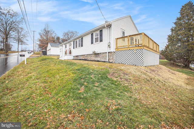 view of property exterior featuring a wooden deck and a lawn