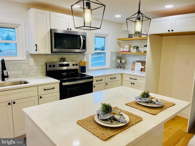 kitchen featuring pendant lighting, backsplash, sink, light hardwood / wood-style floors, and stainless steel appliances