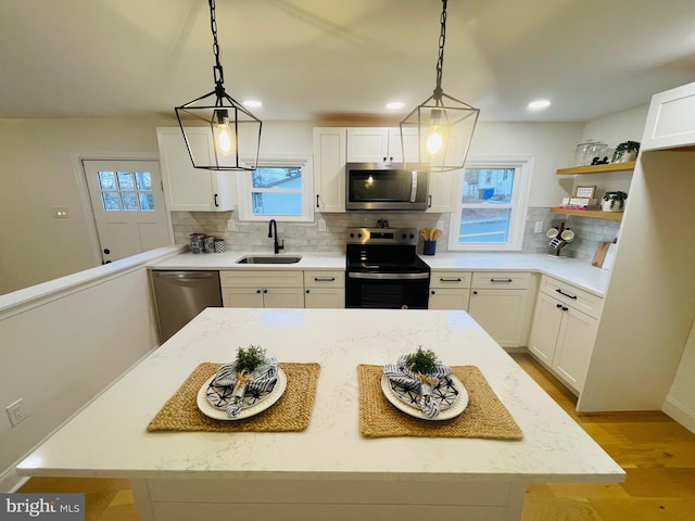 kitchen with white cabinetry, sink, hanging light fixtures, and appliances with stainless steel finishes