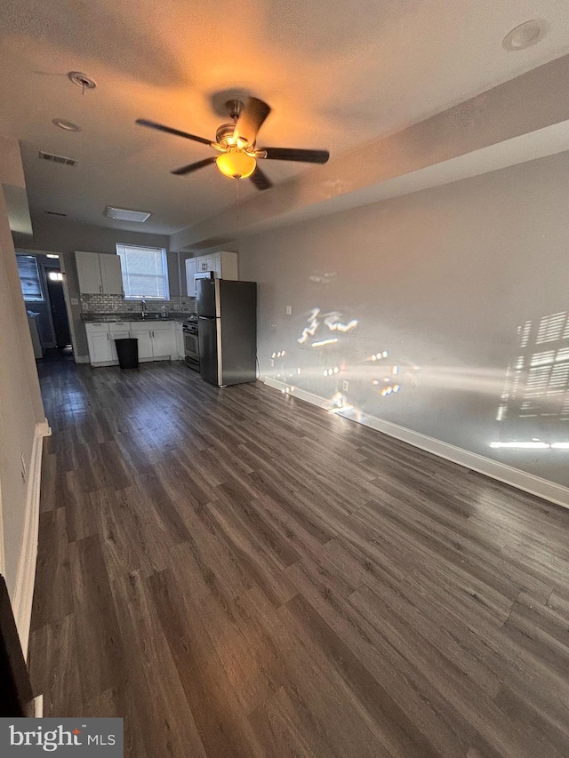 unfurnished living room featuring dark hardwood / wood-style floors, ceiling fan, sink, and a textured ceiling