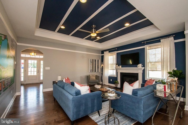 living room with dark hardwood / wood-style floors, ceiling fan, and a raised ceiling