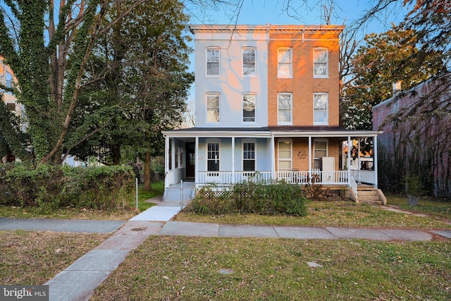 italianate-style house featuring covered porch and a front yard