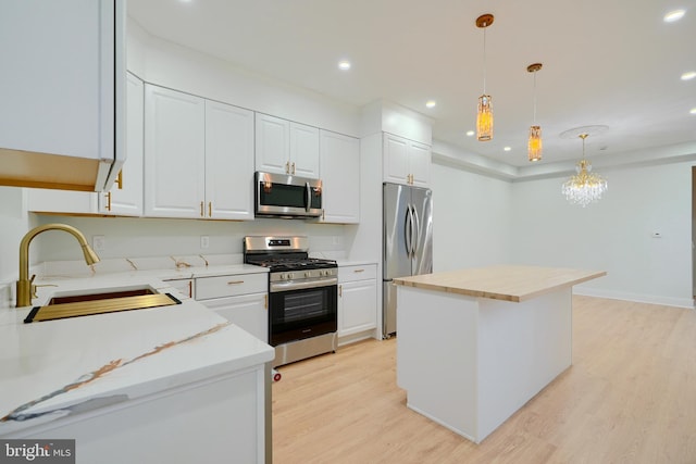 kitchen featuring white cabinets, a kitchen island, sink, and stainless steel appliances