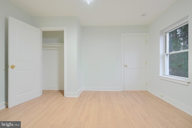 unfurnished bedroom with light wood-type flooring and a closet