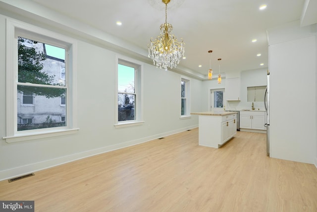 kitchen featuring white cabinetry, light hardwood / wood-style flooring, a kitchen island, and hanging light fixtures