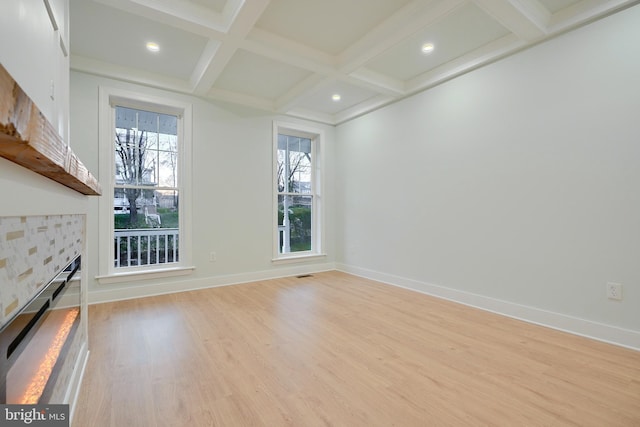 unfurnished living room with a fireplace, beam ceiling, light wood-type flooring, and coffered ceiling