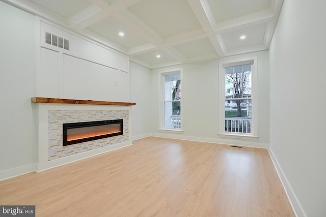 unfurnished living room with a fireplace, beam ceiling, light hardwood / wood-style floors, and coffered ceiling