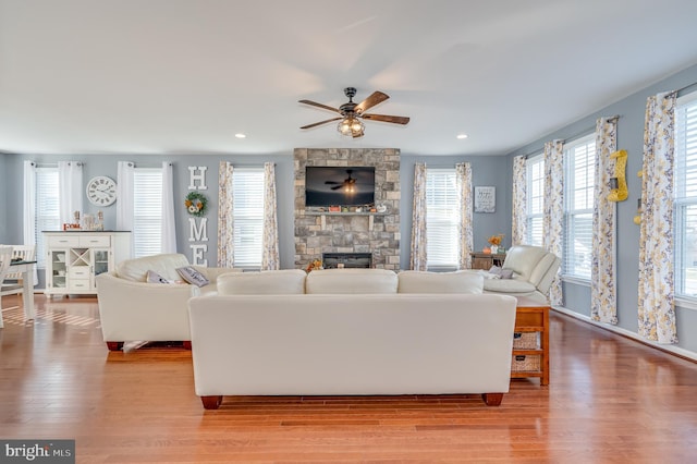 living room featuring a fireplace, light hardwood / wood-style flooring, and ceiling fan