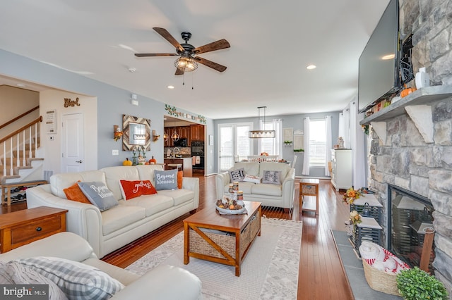 living room featuring ceiling fan, light hardwood / wood-style floors, and a fireplace