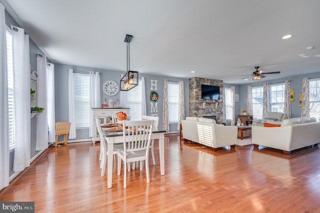 dining room with ceiling fan, wood-type flooring, and a fireplace