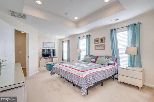 bedroom with light carpet and a tray ceiling