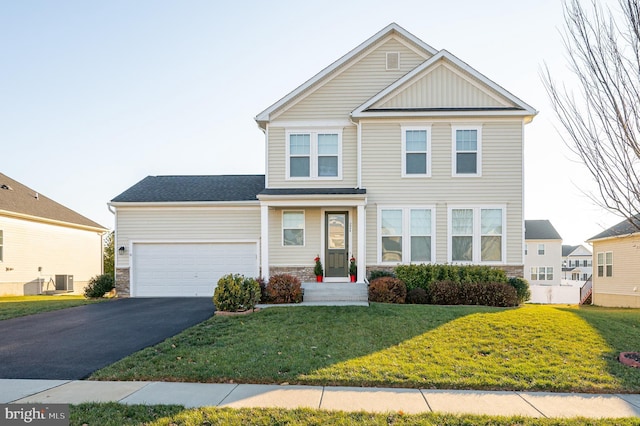 view of front of house with a front yard, central AC, and a garage