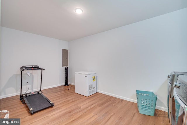 exercise area with independent washer and dryer, electric panel, and light hardwood / wood-style floors