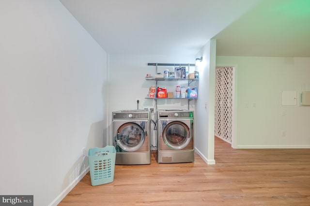 laundry area with washing machine and dryer and light hardwood / wood-style flooring