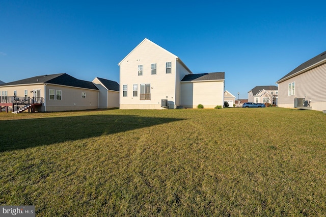 rear view of property featuring central AC and a lawn