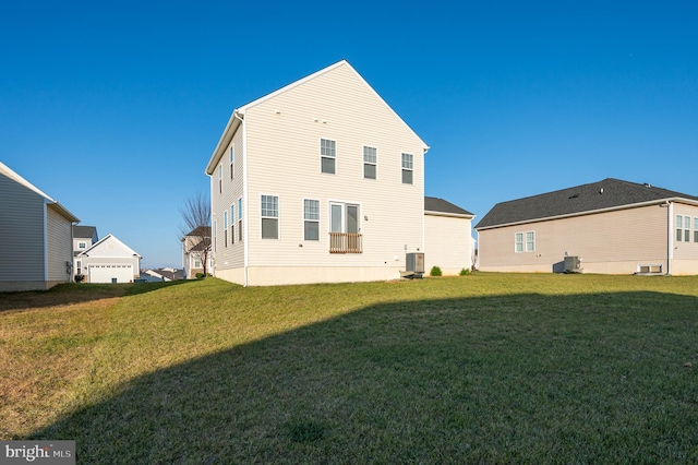 rear view of house featuring central air condition unit and a yard