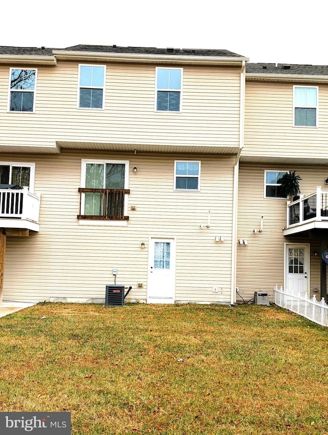 rear view of house with central AC and a lawn