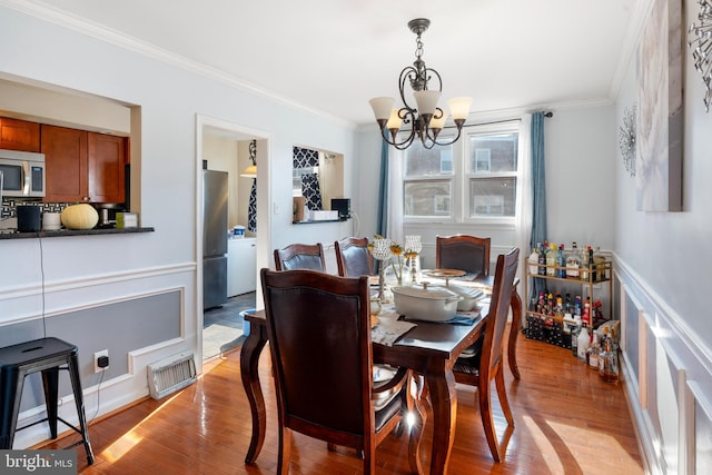 dining space featuring a chandelier, light hardwood / wood-style floors, and crown molding